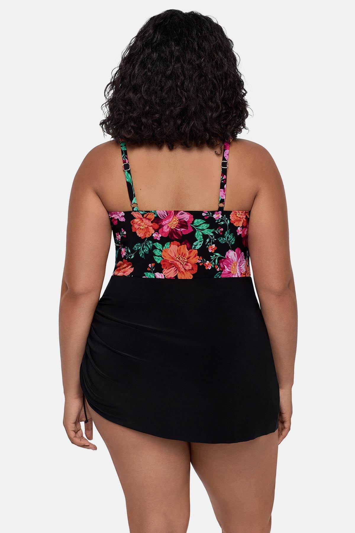 Woman turned away wearing a pink and orange floral printed swim dress