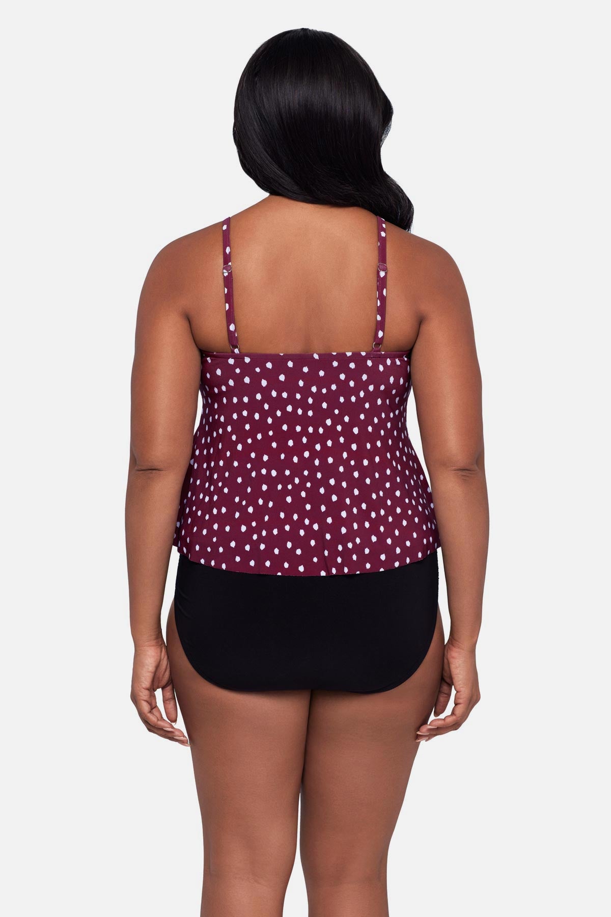 Woman turned away wearing a maroon and white polka dot tankini top with ruffles