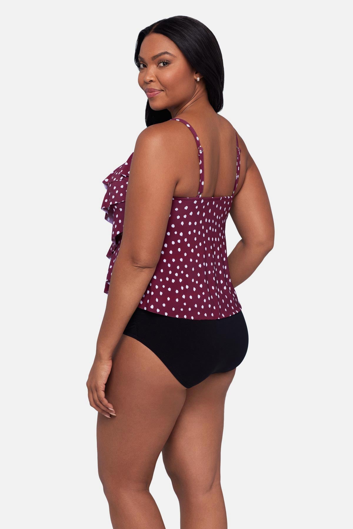 Woman turned left wearing a maroon and white polka dot tankini top with ruffles