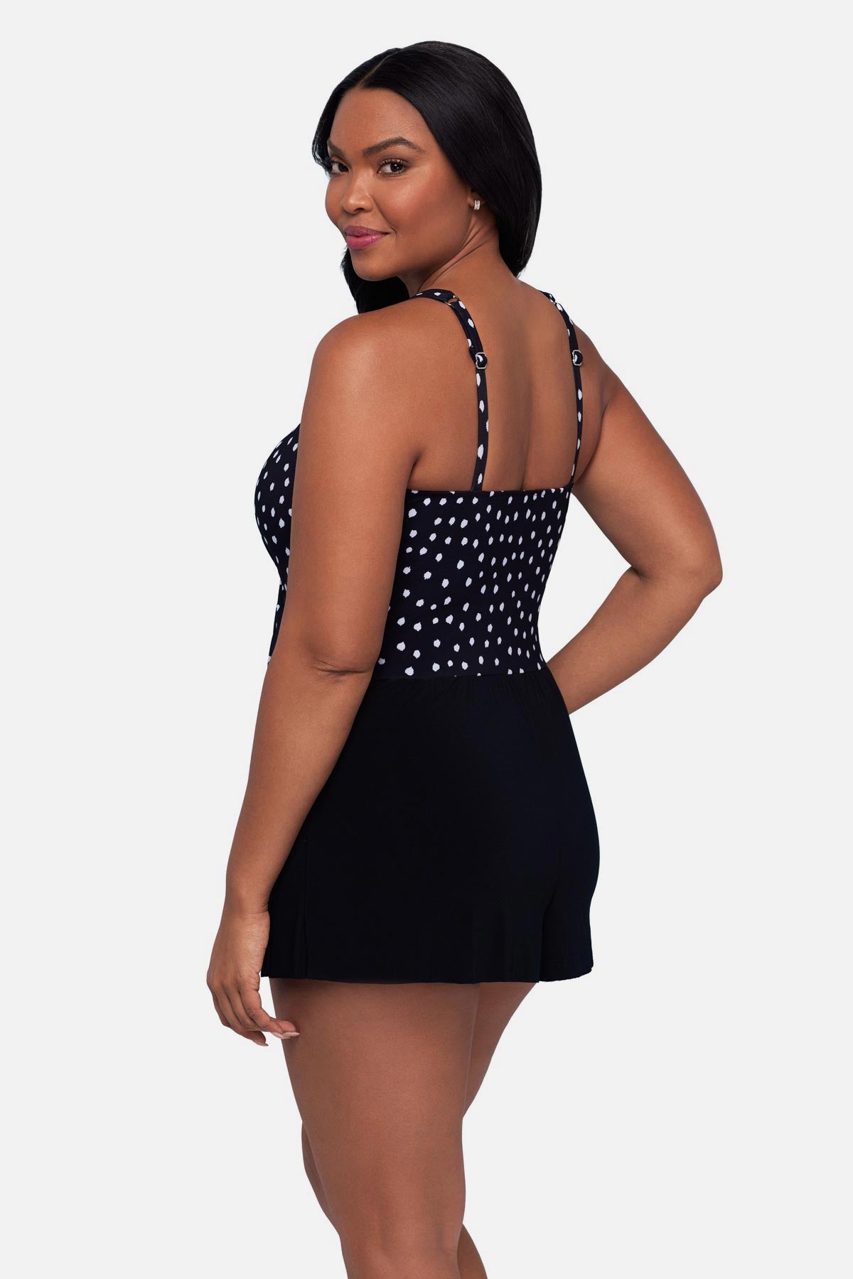 Woman turned left wearing a black and white polka dot swim romper