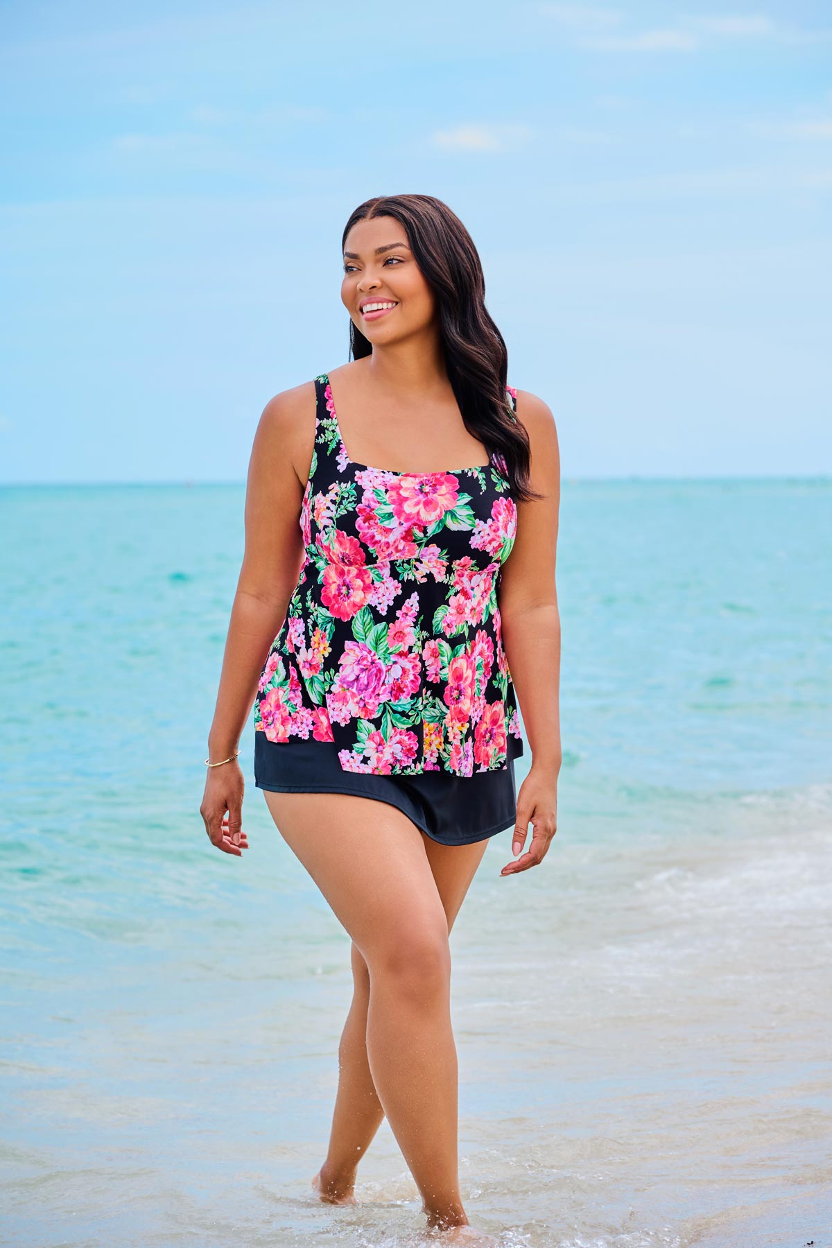 Woman on beach wearing a pink floral print tankini top