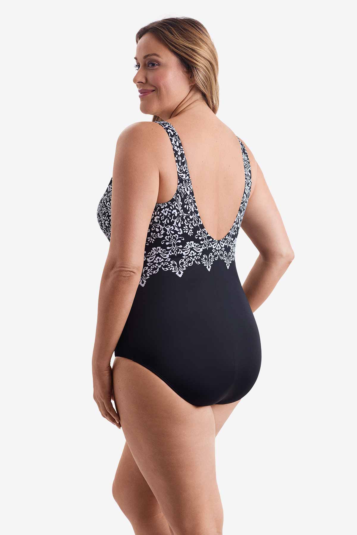 Woman turned left wearing a one-piece swimsuit with an abstract black and white pattern