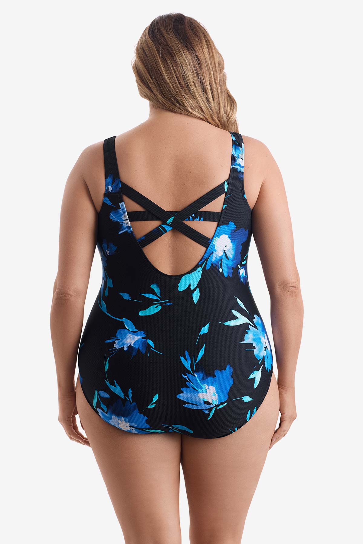 Woman turned away wearing a large blue floral printed one-piece swimsuit with an X back