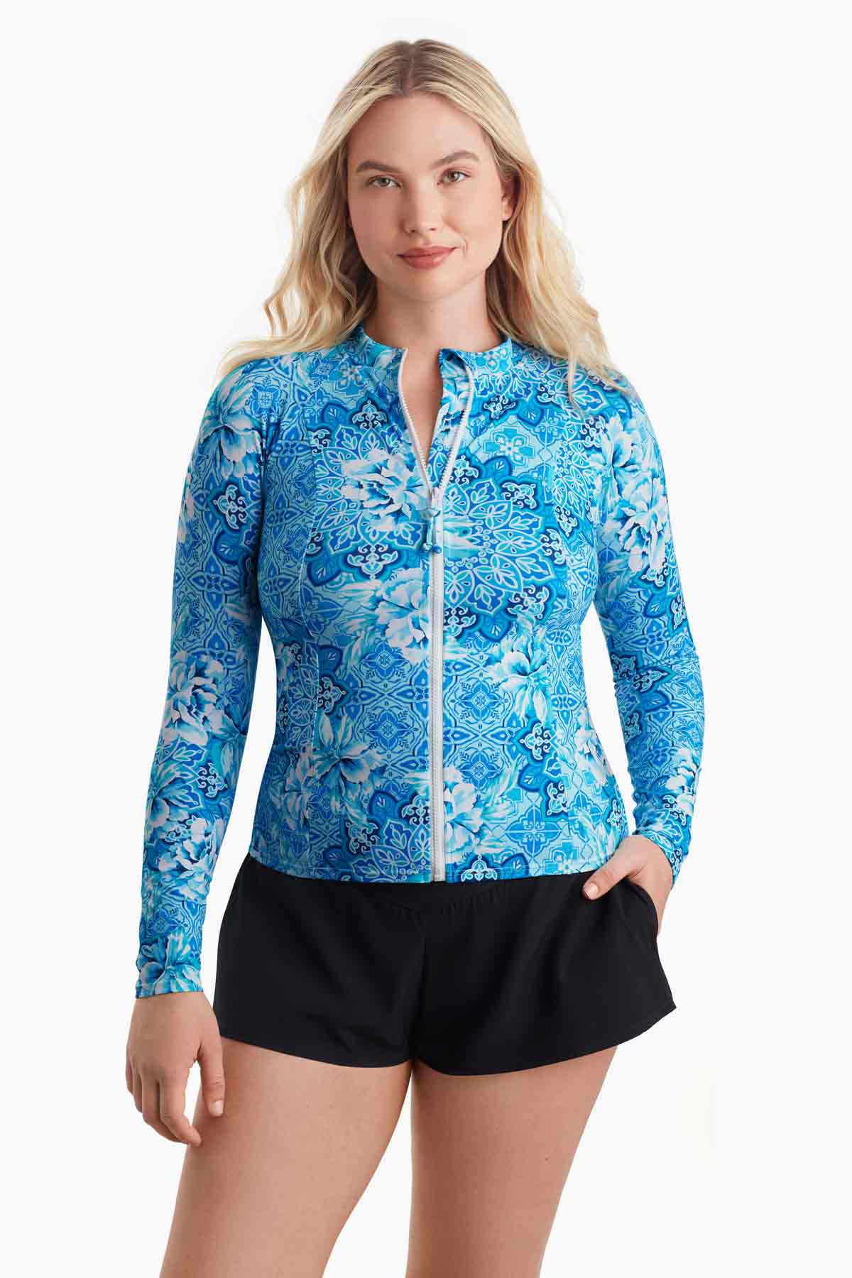 Woman wearing a blue abstract printed sun shirt with a zipper down the front with her hand in pocket