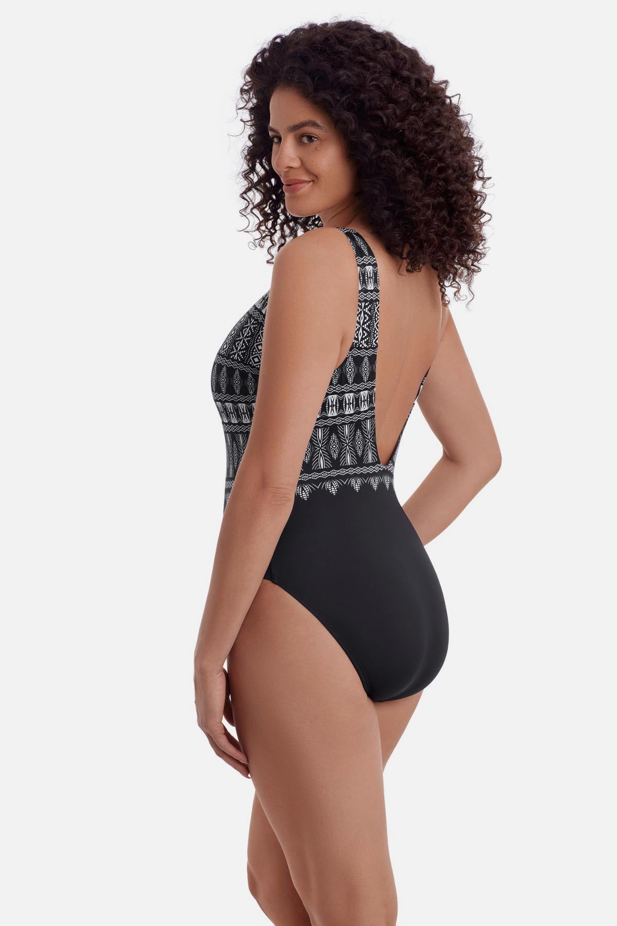 Woman faced left wearing a black and white tribal printed one-piece swimsuit with a high neckline