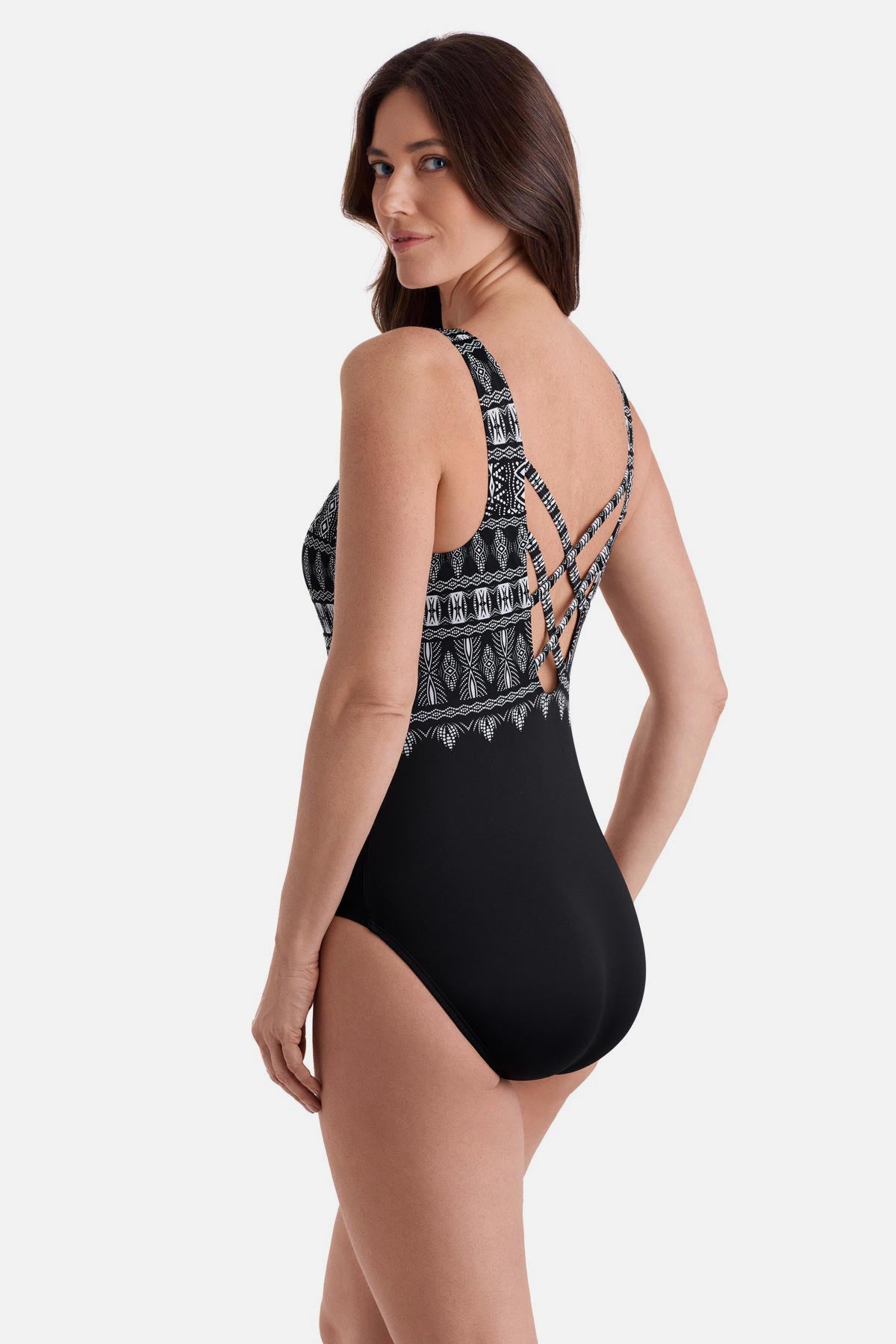 Woman turned left wearing a black and white tribal printed one-piece swimsuit with a cross back