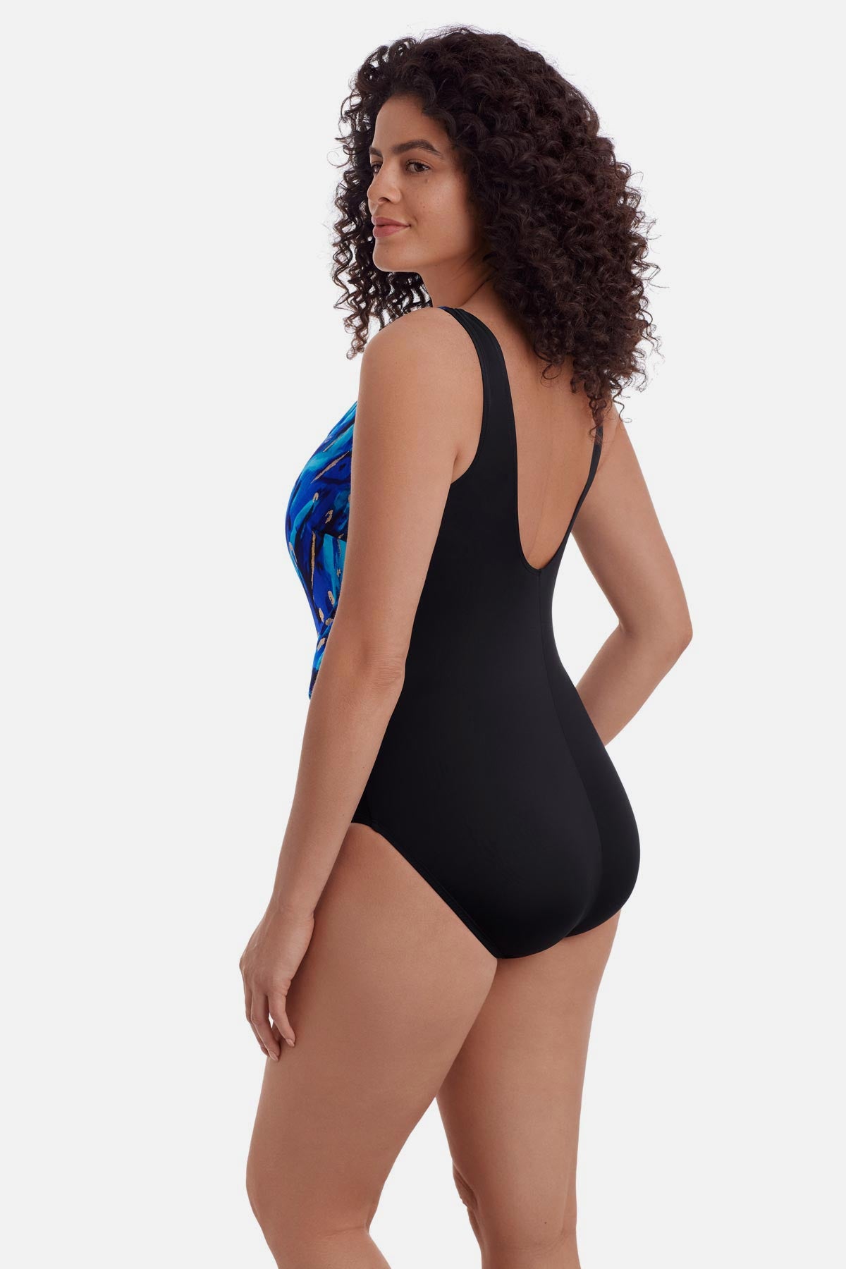 Woman turned left wearing a blue and gold accented print one-piece swimsuit with a pull up sash