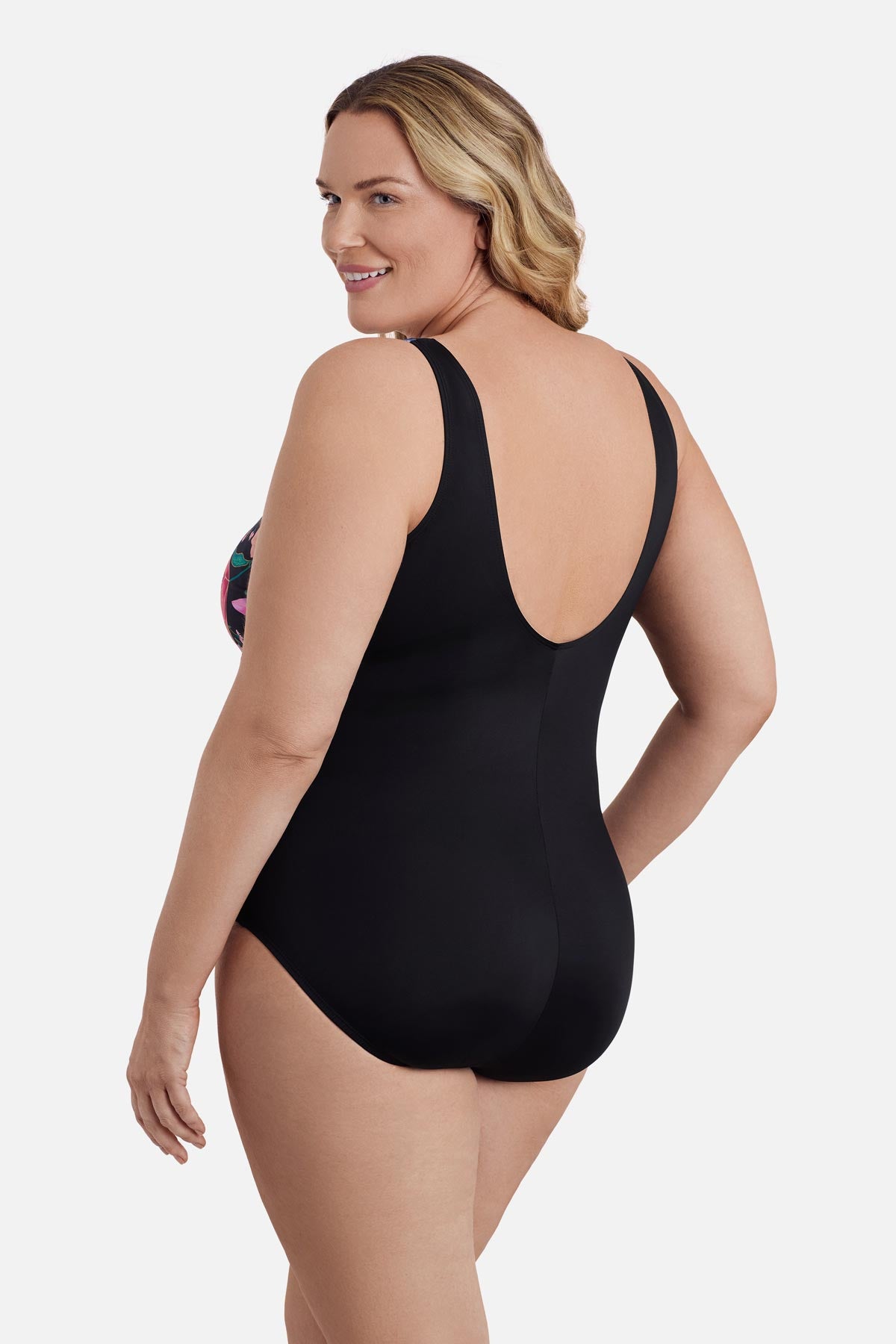 Woman turned left wearing a multicolored floral and palm leaf printed one-piece swimsuit
