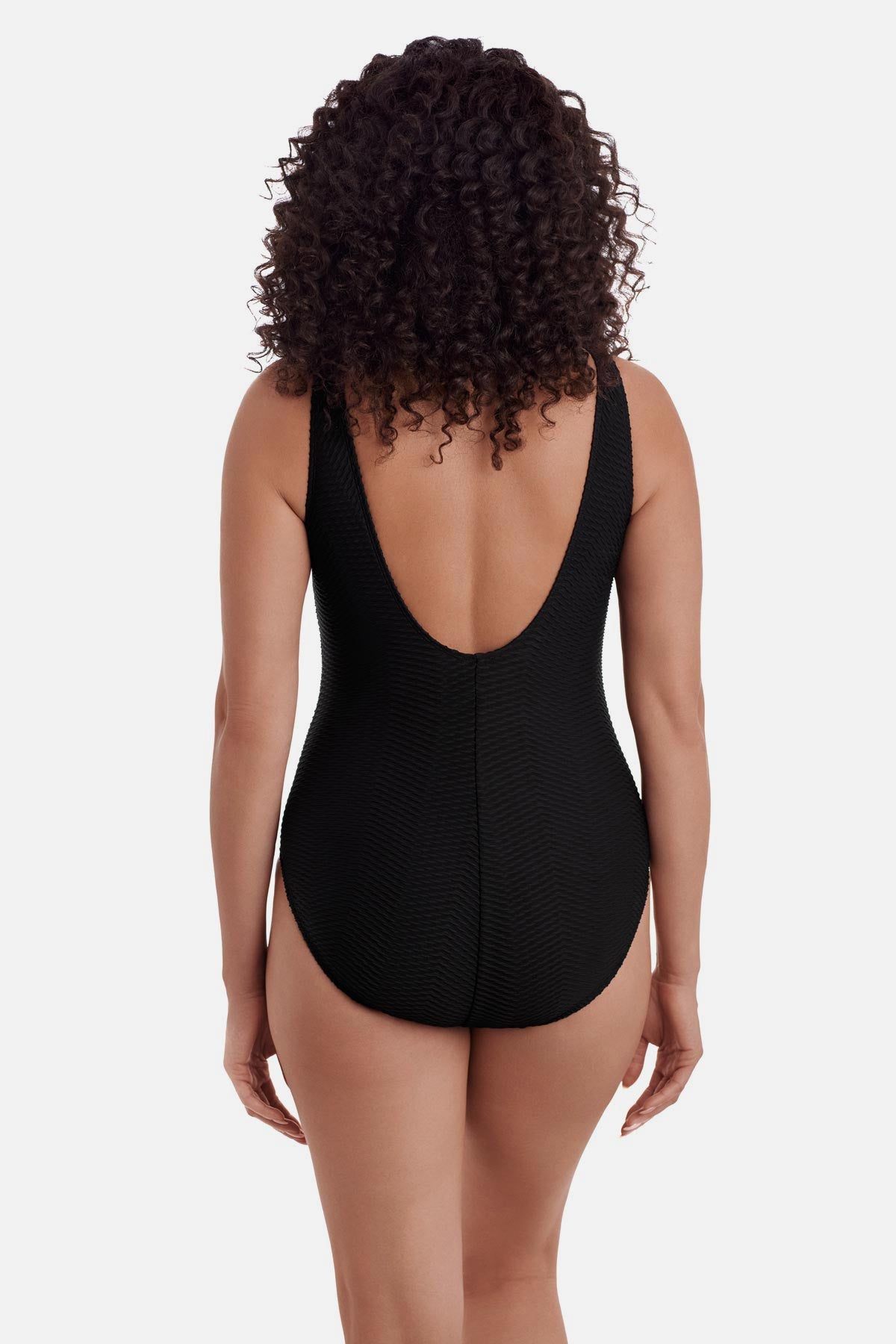 Woman turned away wearing a black one-piece swimsuit with a scoop back