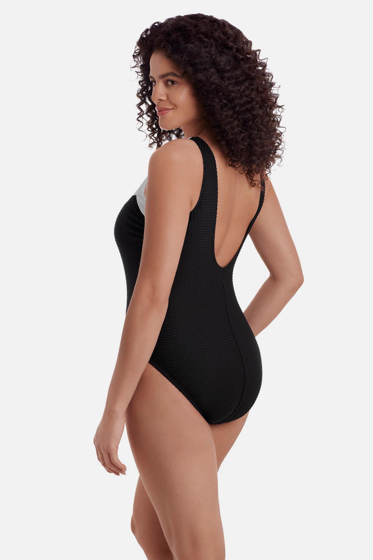 Woman turned left wearing a black one-piece swimsuit with white trim along the straps and neckline