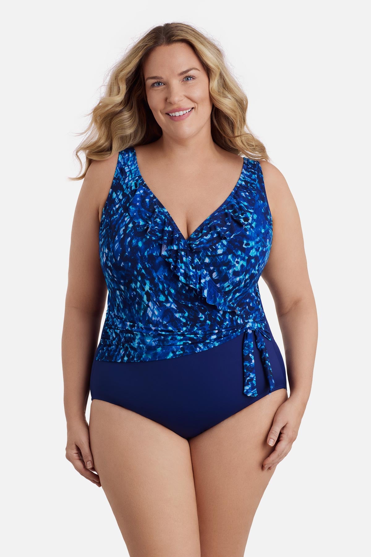 Woman wearing a navy blue abstract printed one-piece swimsuit with ruffles on the neckline
