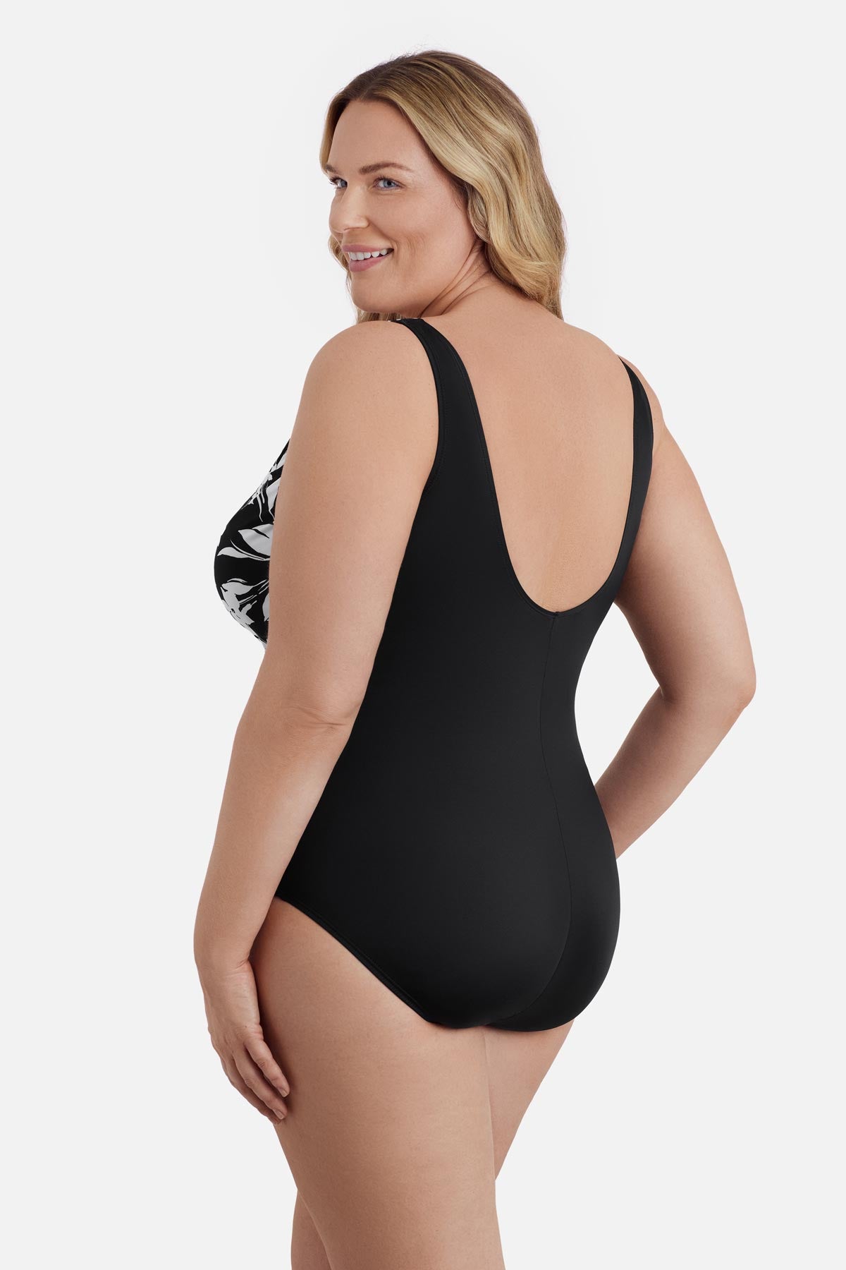 Woman turned left wearing a black and white floral one-piece swimsuit