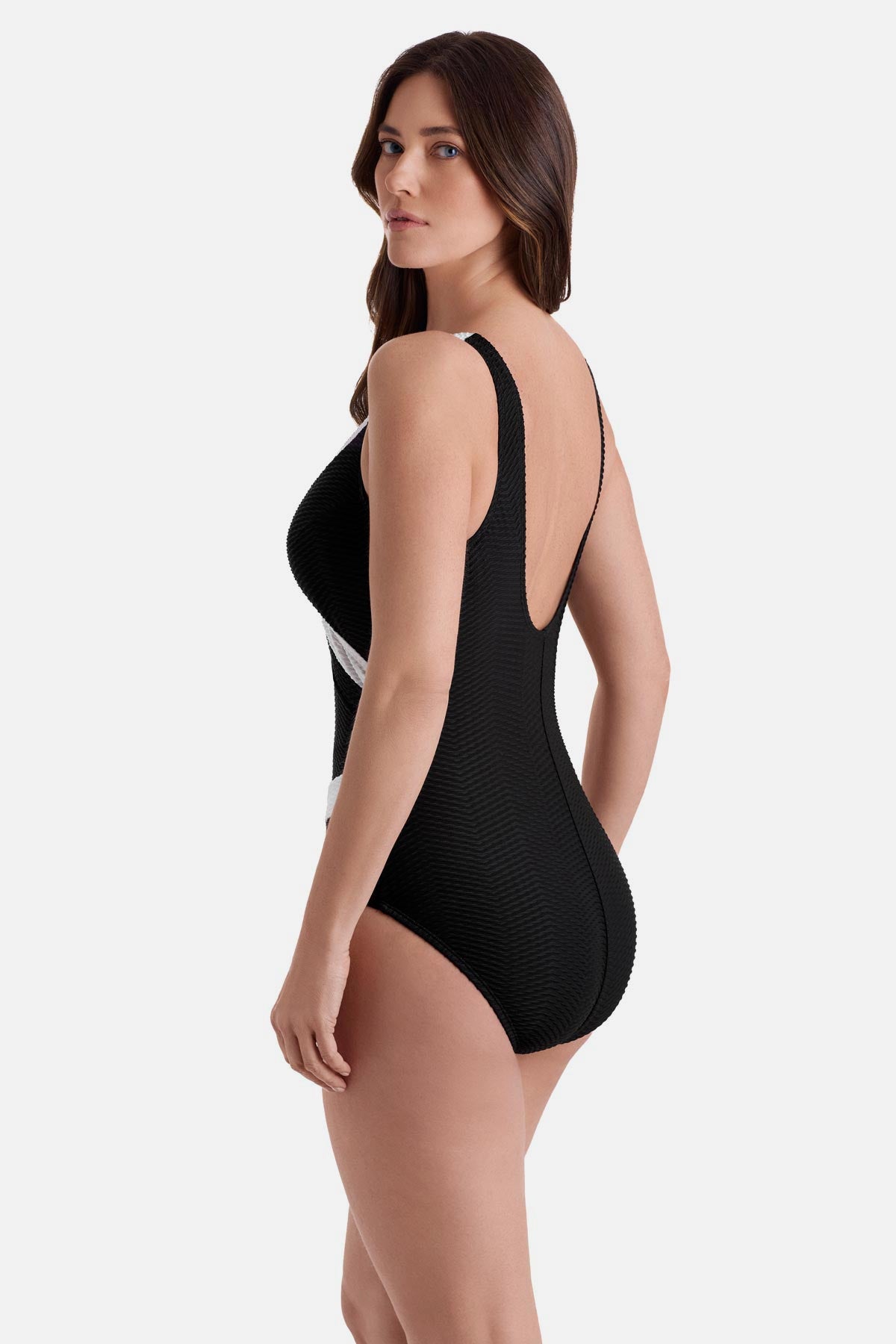 Woman turned left wearing a black one-piece swimsuit with white textured trim