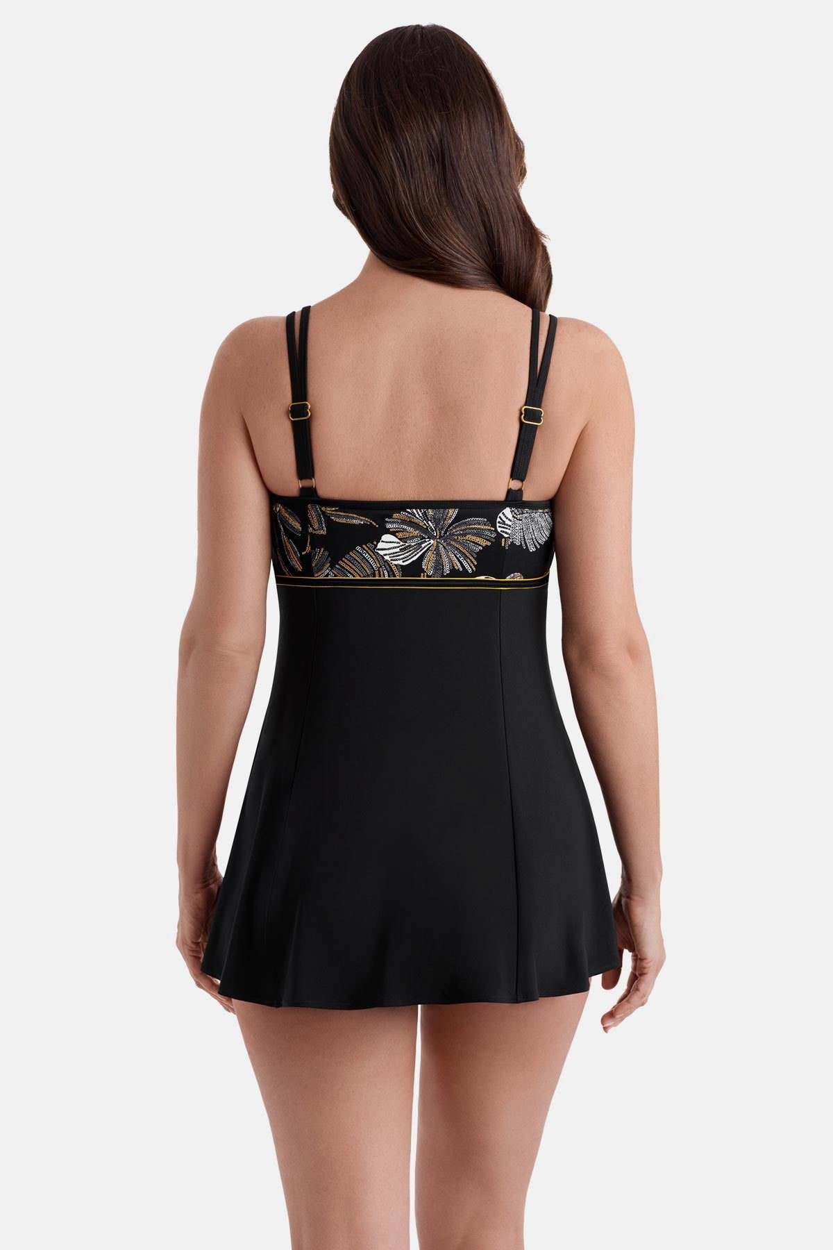 Woman turned away wearing a swim dress with white and gold floral print on the bust