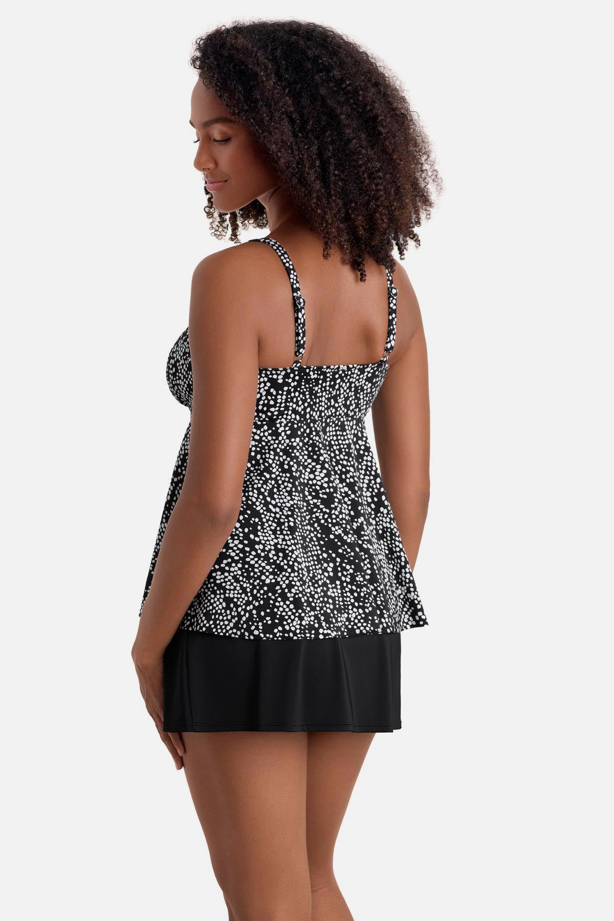 Woman turned left wearing a black and white dotted print tankini top