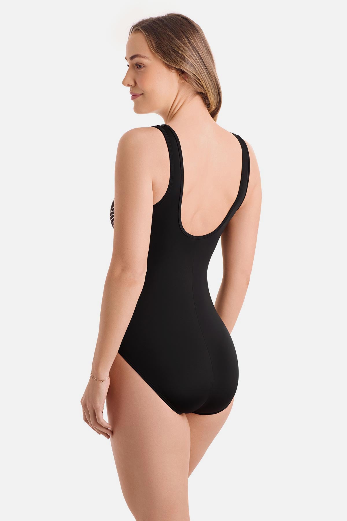 Woman turned left wearing a black and white maze print one-piece swimsuit with a zipper down the front