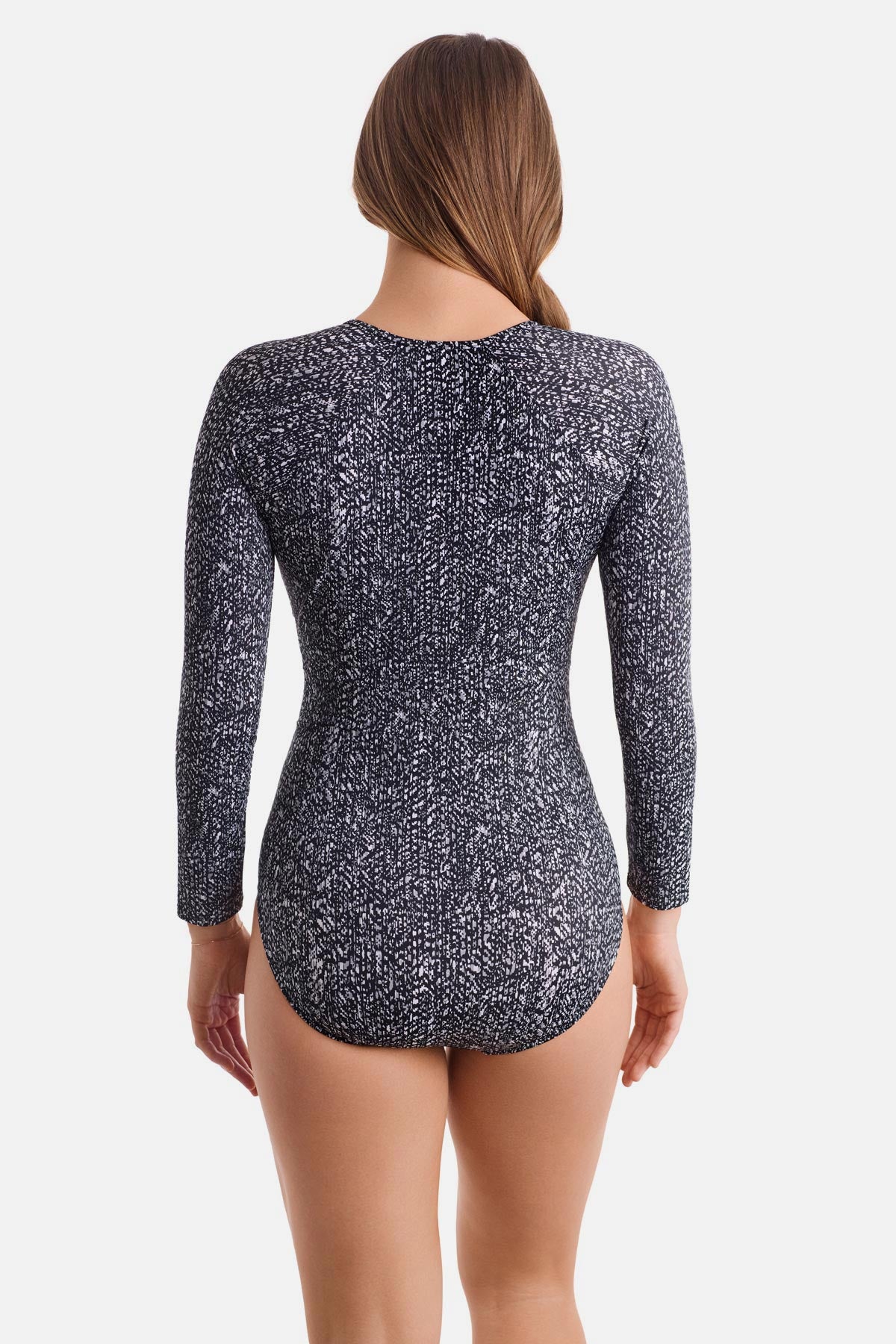 Woman turned away wearing a long sleeve one-piece swimsuit with a black and white abstract print