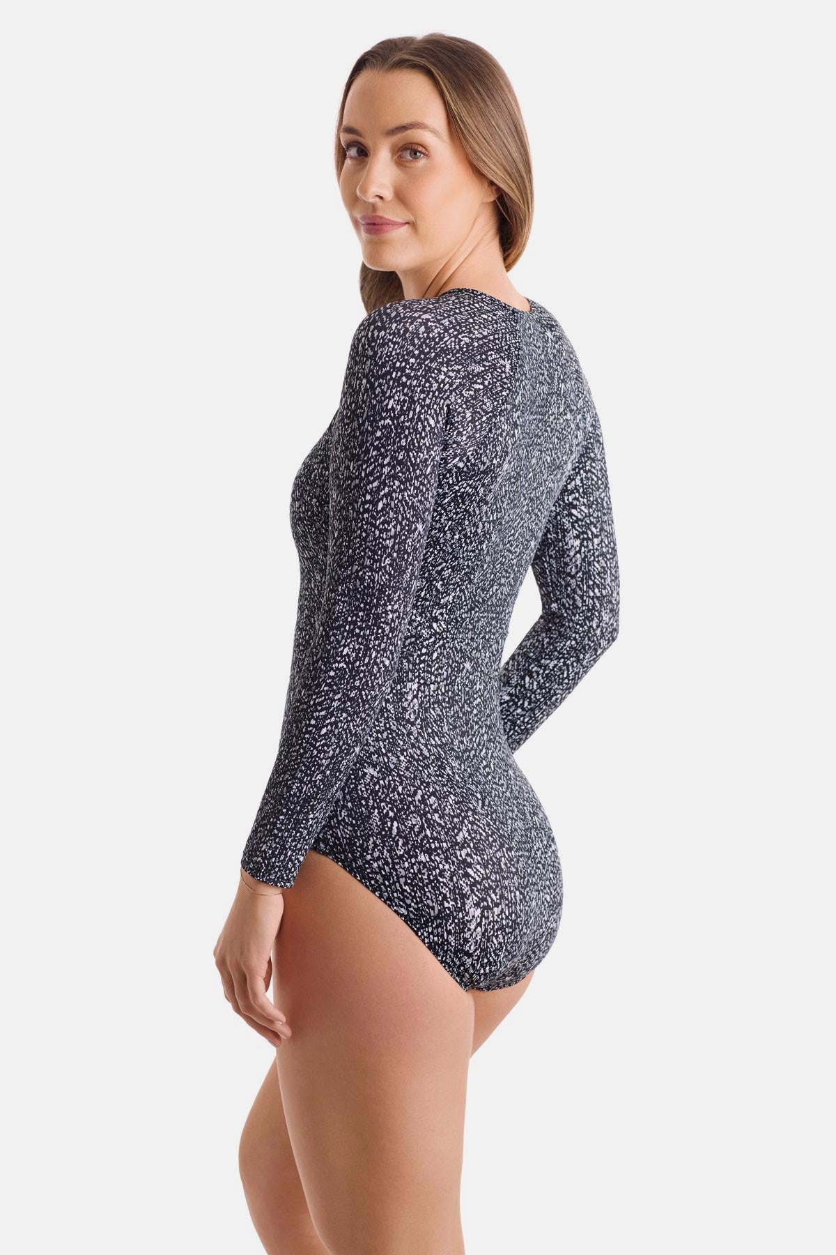 Woman turned left wearing a long sleeve one-piece swimsuit with a black and white abstract print