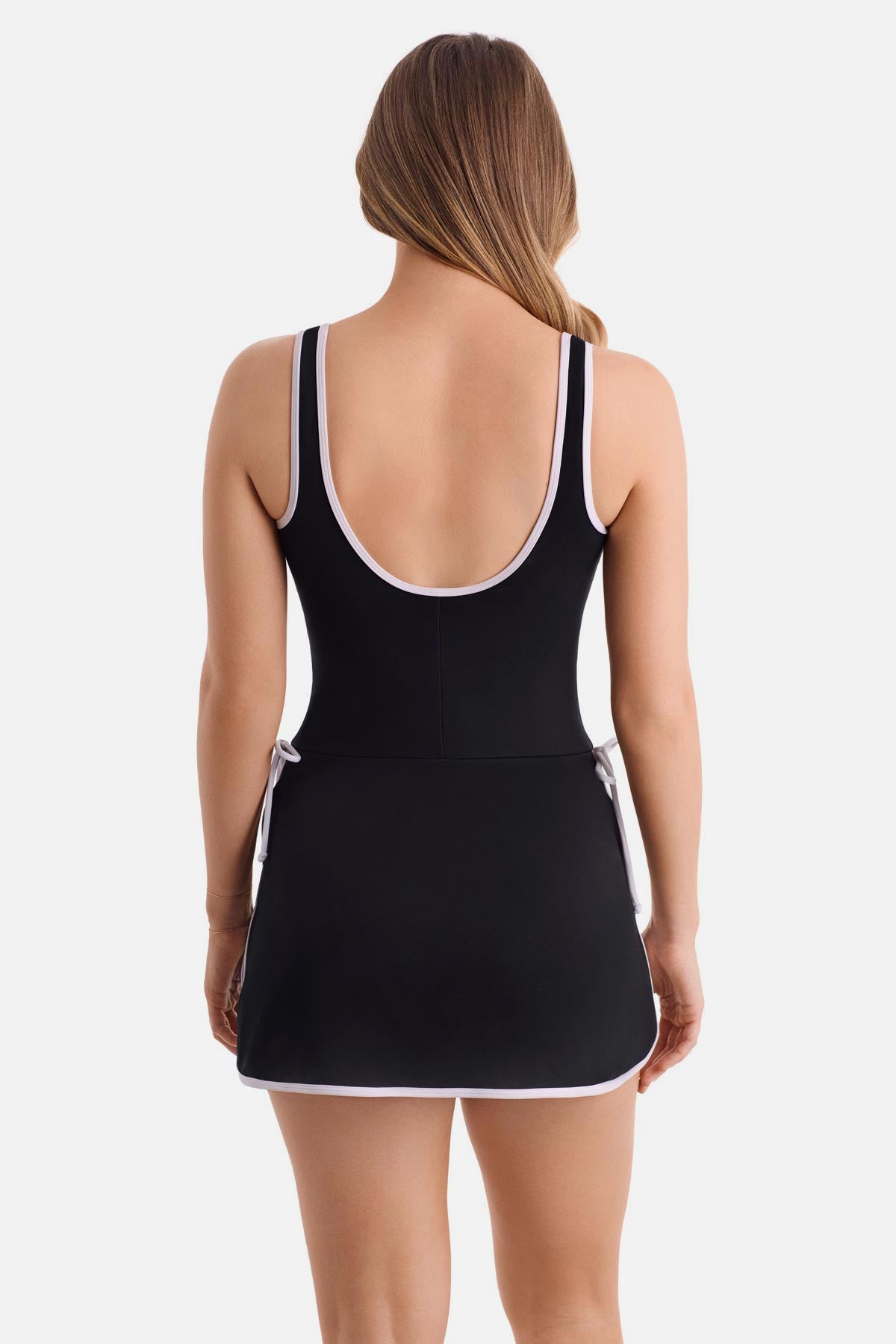Woman turned away wearing a black swim dress with white piping/edges