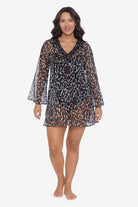 Woman wearing an animal printed sheer swim cover up with black trim on the neckline