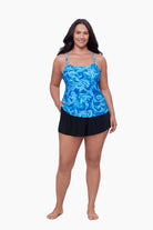 Woman wearing a swim romper with a blue abstract print with hand in pocket