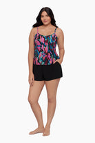 Woman wearing a swim romper with a collage patchwork patter with her hand in pocket 