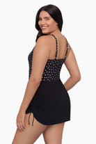 Woman turned left wearing a swim dress with black and white polka dots