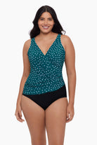 Woman wearing a one-piece swimsuit with a teal and white dot pattern
