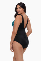 Woman turned left wearing a one-piece swimsuit with a teal and white dot pattern