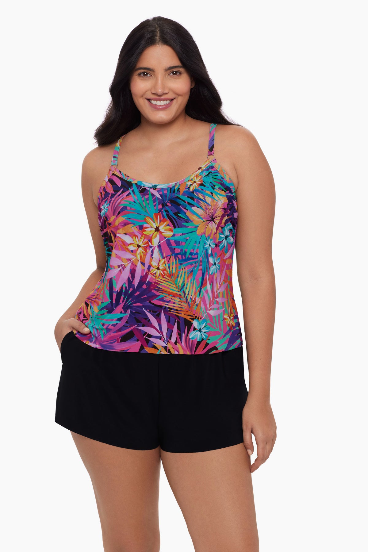 Woman wearing a swim romper with a neon palm leaf print and her hand in pocket