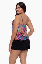 Woman turned left wearing a swim romper with a neon palm leaf print 