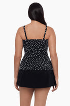 Woman turned away wearing a tankini top with black and white polka dots 