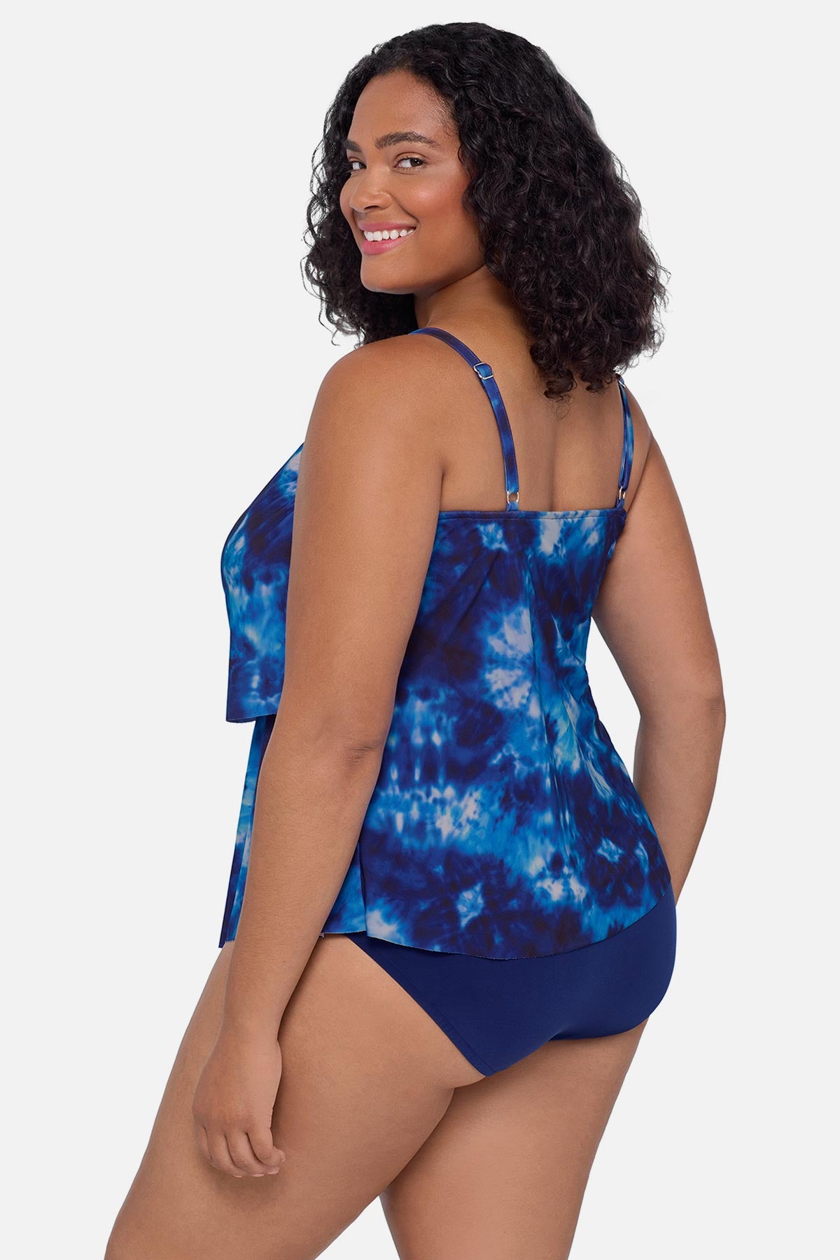 Woman turned left wearing a blue tie dye tankini top with ruffles