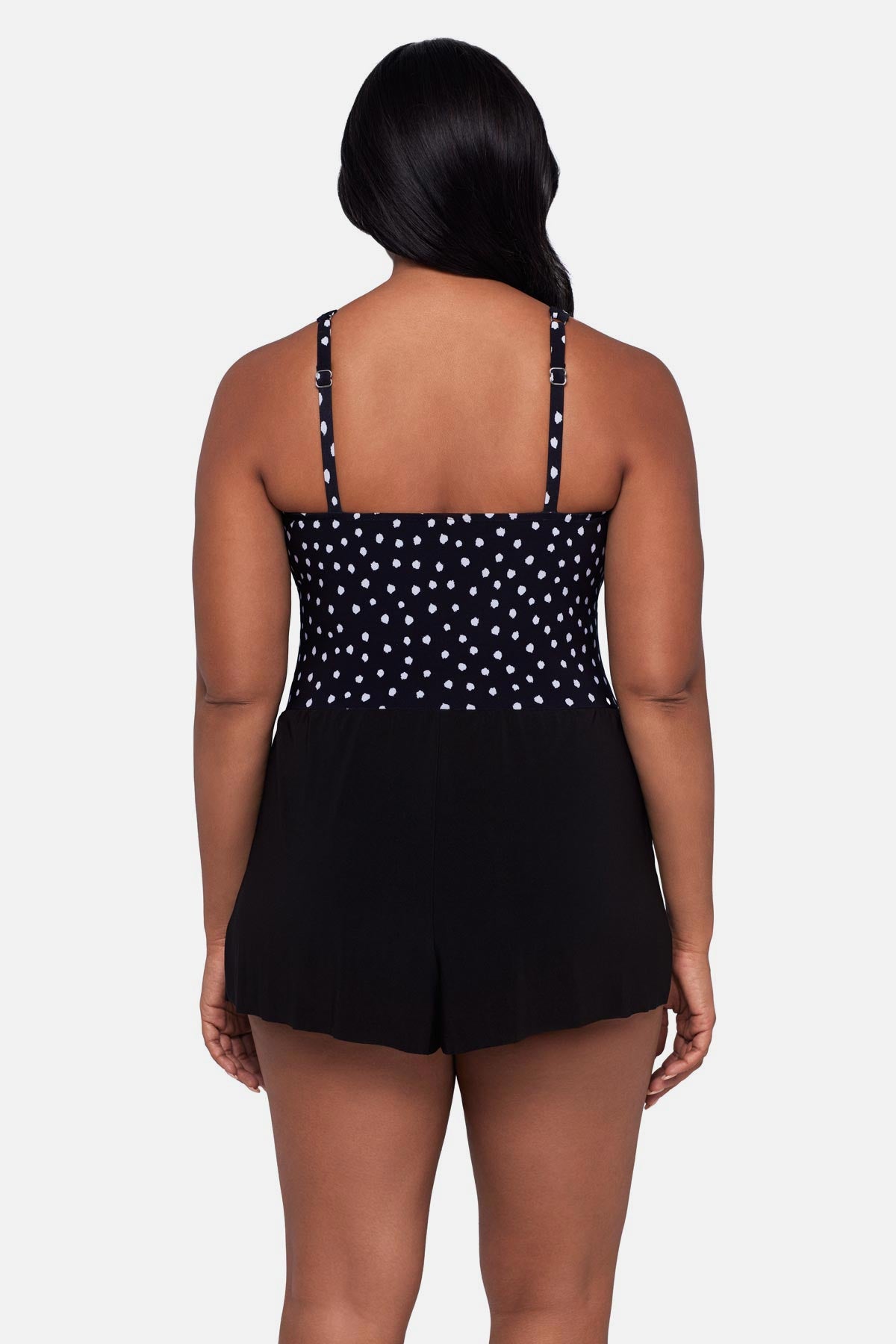 Woman turned away wearing a black and white polka dot swim romper