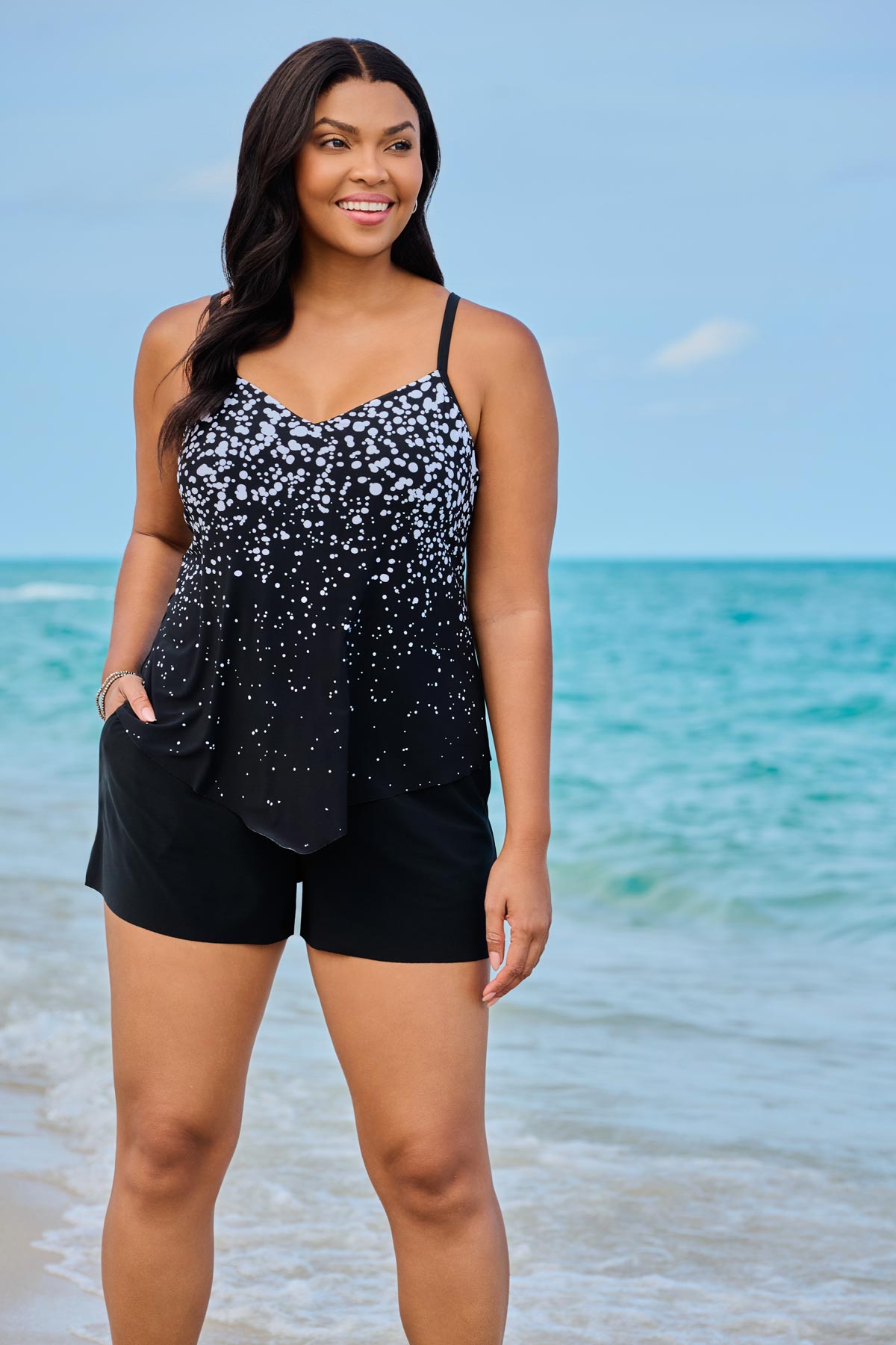 Woman on beach wearing a black and white dotted swim romper