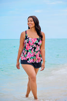 Woman on beach wearing a pink floral print tankini top