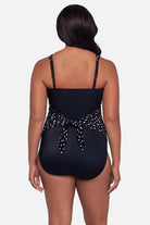 Woman turned away wearing a black and white polka dot one-piece swimsuit