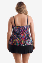 Woman turned away wearing a tiered one-piece swimsuit with an abstract rainbow pattern