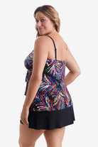 Woman turned left wearing a tiered one-piece swimsuit with an abstract rainbow pattern