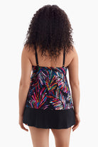 Woman turned away wearing a one-piece swimsuit with an abstract rainbow print