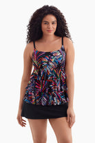 Woman wearing a tiered one-piece swimsuit with an abstract rainbow print