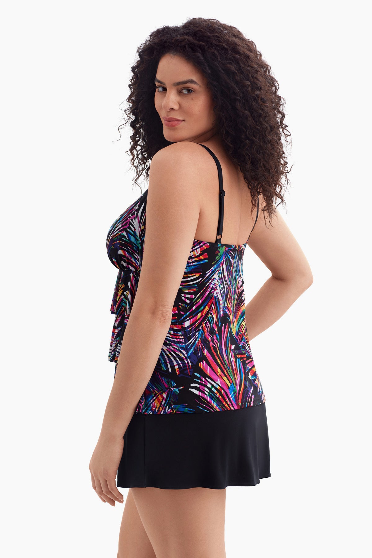 Woman turned left wearing a tiered one-piece swimsuit with an abstract rainbow print
