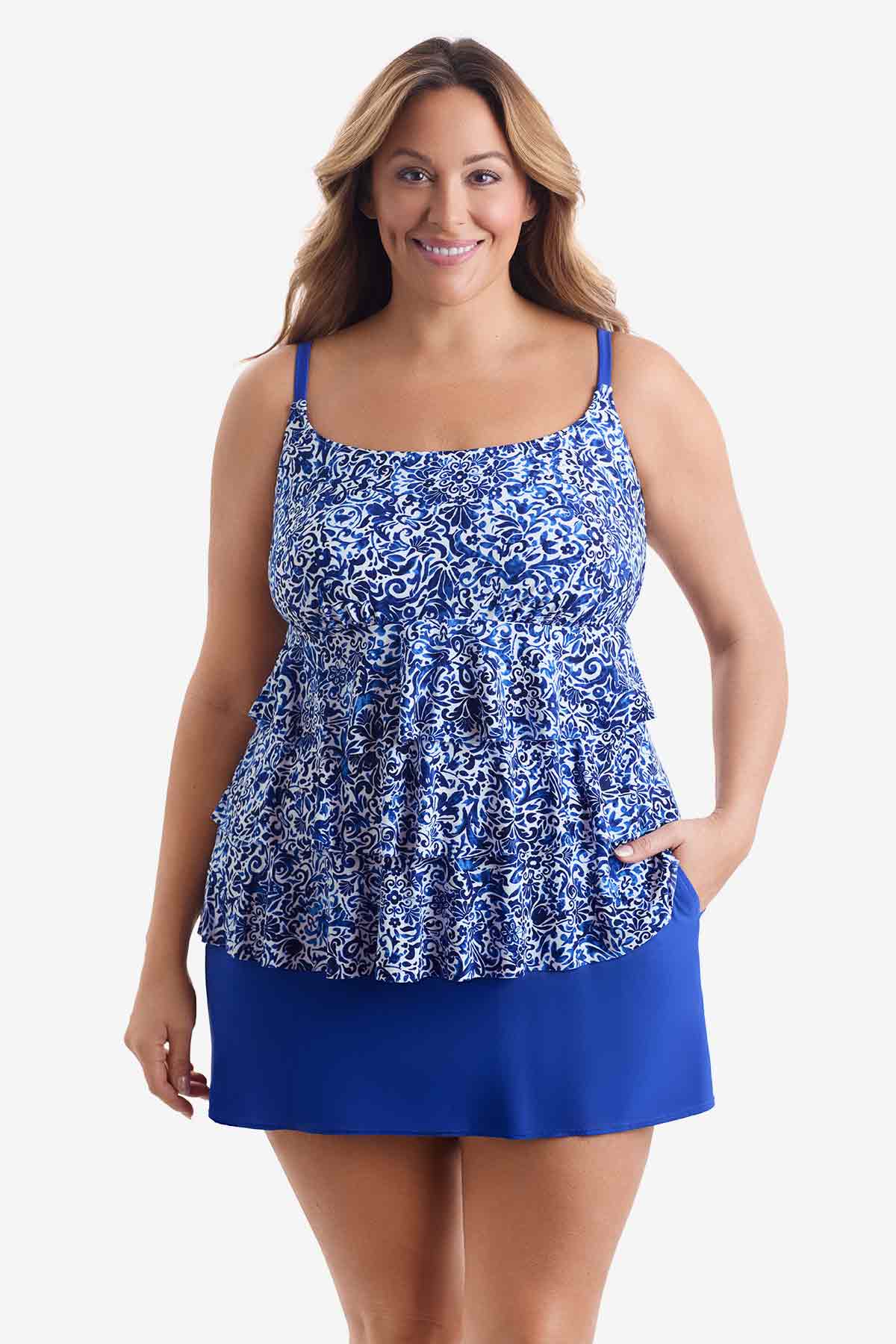 Woman wearing a blue and white patterned tiered one-piece swimsuit with her hand in pocket