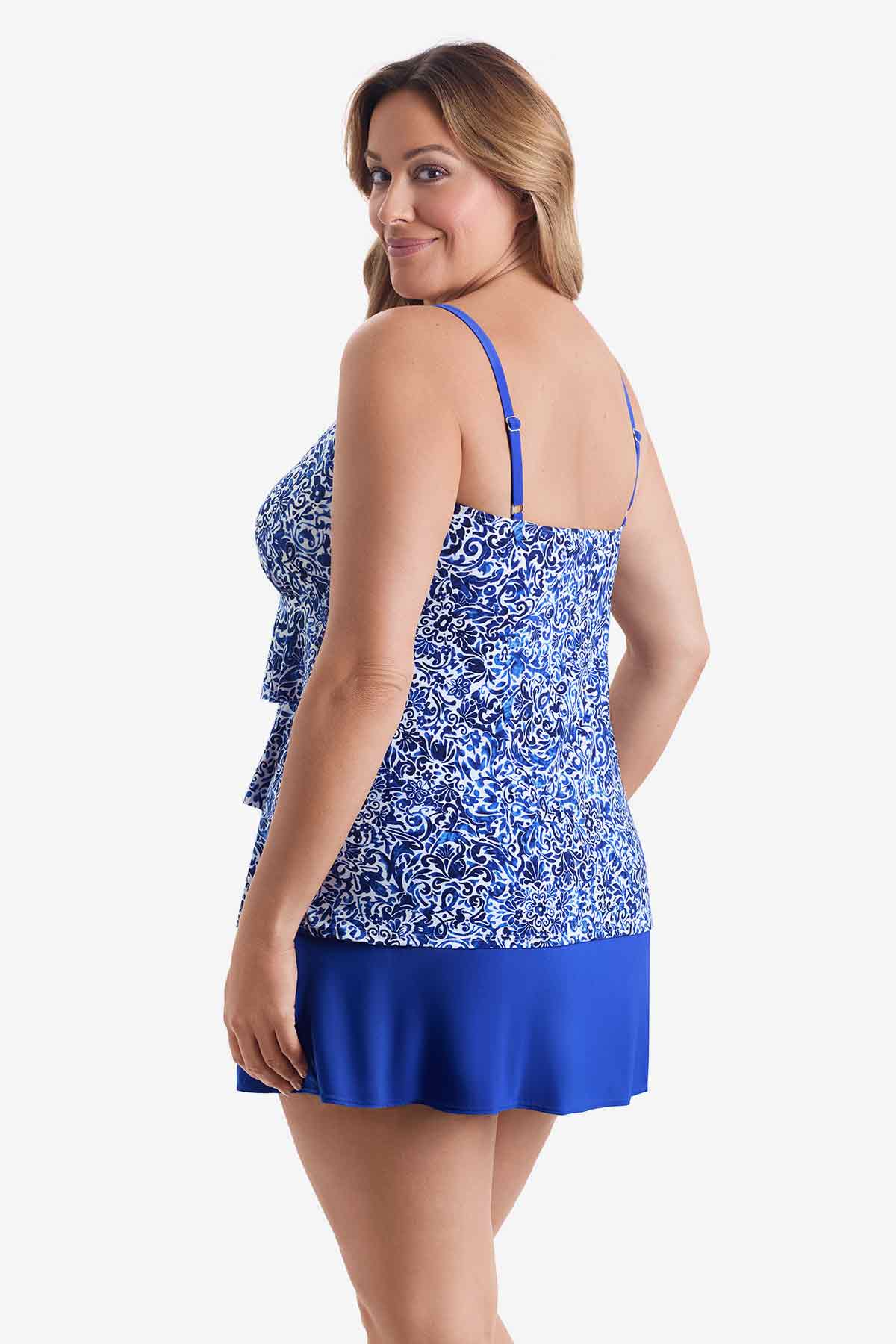 Woman faced left wearing a blue and white patterned tiered one-piece swimsuit 