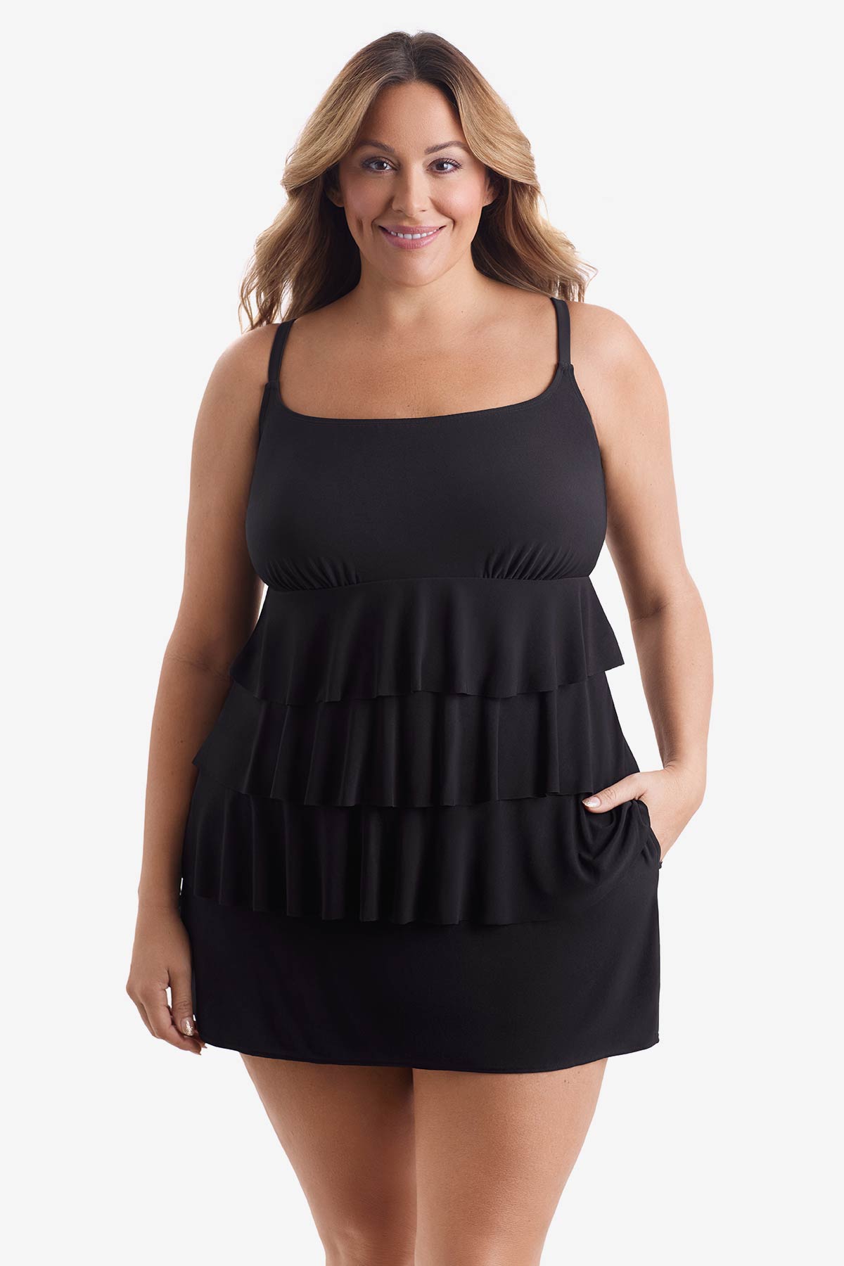 Woman wearing a black tiered one-piece swimsuit with hand in pocket