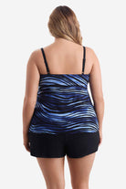 Woman turned away wearing a tiered one-piece swimsuit with a black and blue pattern