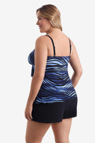 Woman turned left wearing a tiered one-piece swimsuit with a black and blue pattern