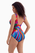 Woman looking left wearing a one-piece swimsuit with a multicolored radial pattern
