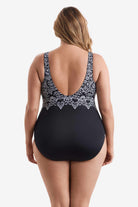 Woman turned away wearing a one-piece swimsuit with an abstract black and white pattern