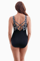 Woman turned away wearing a one-piece swimsuit with a black and white X pattern on the back